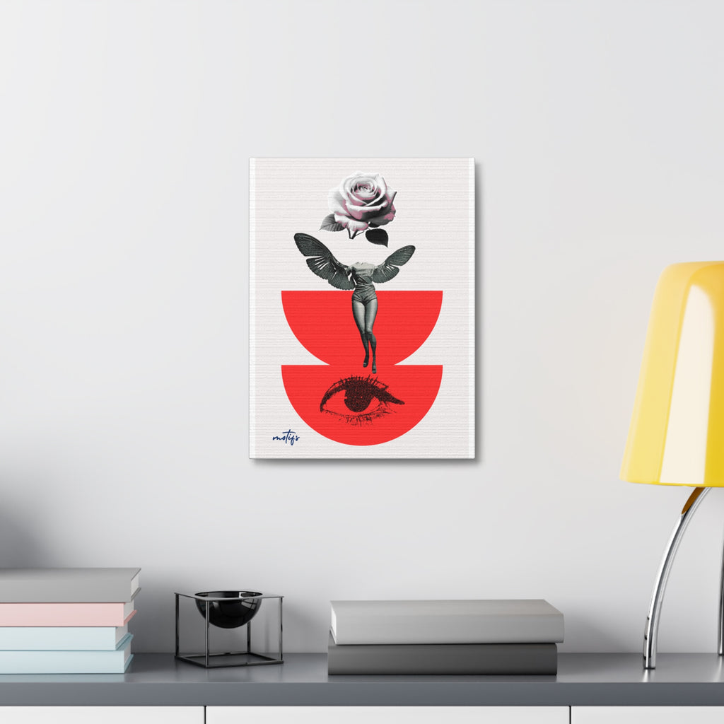 A vertical art print featuring a stylized figure with wings and a rose above a red semicircle, displayed on a light gray wall above a shelf with books and a yellow lamp.