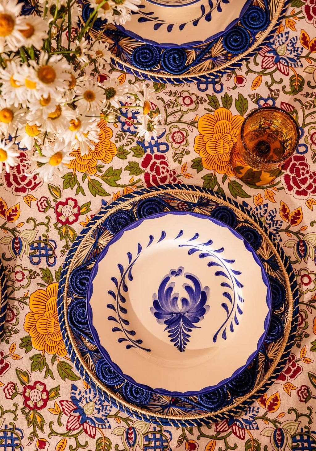 Decorative table setting with floral tablecloth and ornate plates.