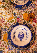 Decorative table setting with floral tablecloth and ornate plates.