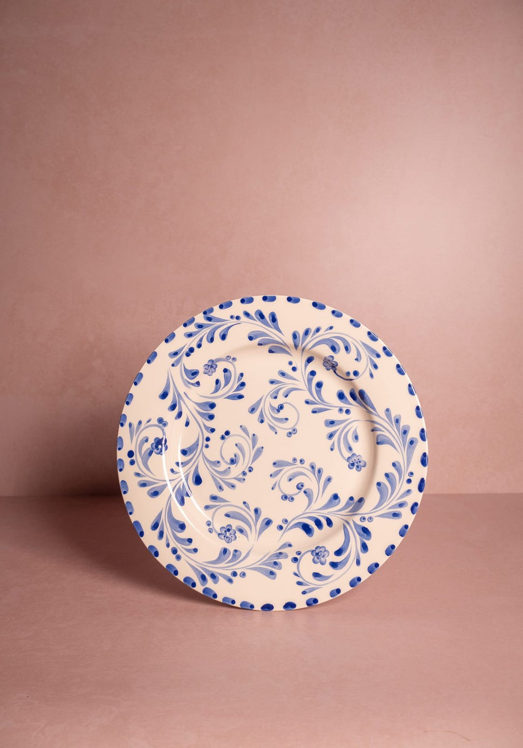 Decorative plate with blue floral pattern on a pink background