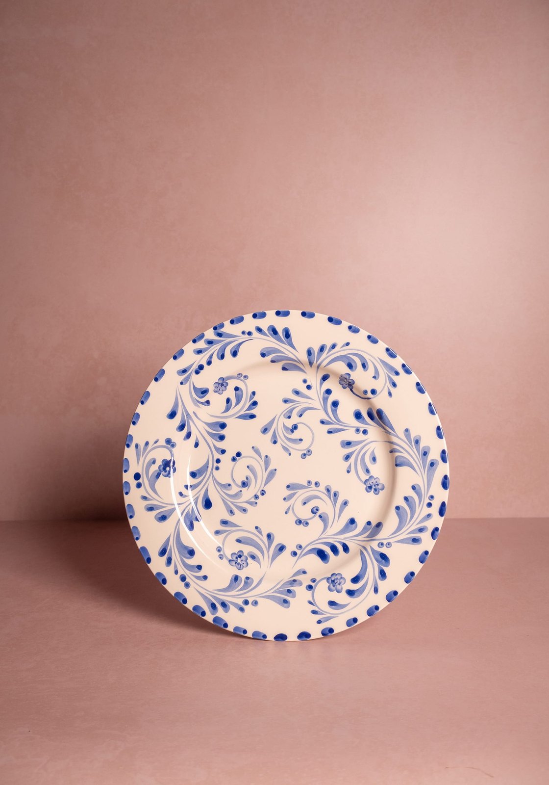 Decorative plate with blue floral pattern on a pink background