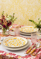Decorative table setting with floral plates, glasses, and a patterned tablecloth.